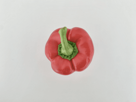 <b>Close-Up of Bell Pepper Stem</b><br>In this shot, I focused on the top of the red bell pepper, showcasing its stem and the rich colors. The green stem contrasts beautifully with the red body, creating an eye-catching visual. The simplicity of the background draws attention to the details, making the pepper look inviting and fresh.