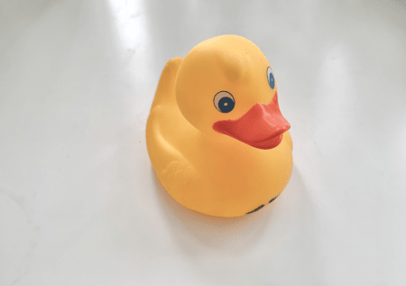 <b>Playful Rubber Duck Photography</b><br>In this photo, I used my phone to capture a cheerful rubber duck, highlighting its bright yellow color and playful expression. The soft lighting enhances the smooth texture of the rubber, making it appear inviting and fun. The simple background keeps the focus on the duck, showcasing its adorable features and making it a delightful subject.