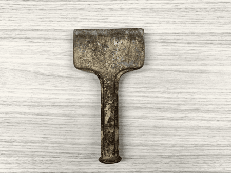 <b>Iron Tool</b><br>This worn iron tool displays a rough, textured surface that reflects its age and use. The rust and imperfections add character, emphasizing the durability of the material. The solid design suggests strength and reliability, typical of tools made from iron.