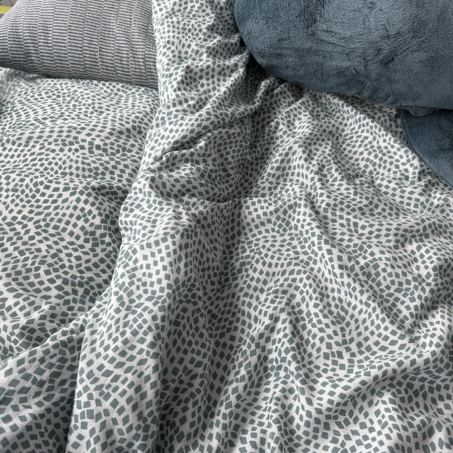 A neatly folded blanket with a geometric pattern, representing the soft rustling sounds of fabric being adjusted and smoothed.