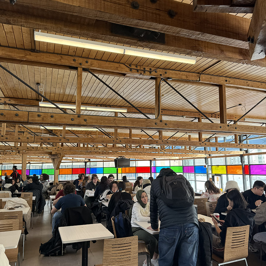 A busy cafeteria with many people seated and talking, depicting the bustling sounds of conversations and laughter among diners.