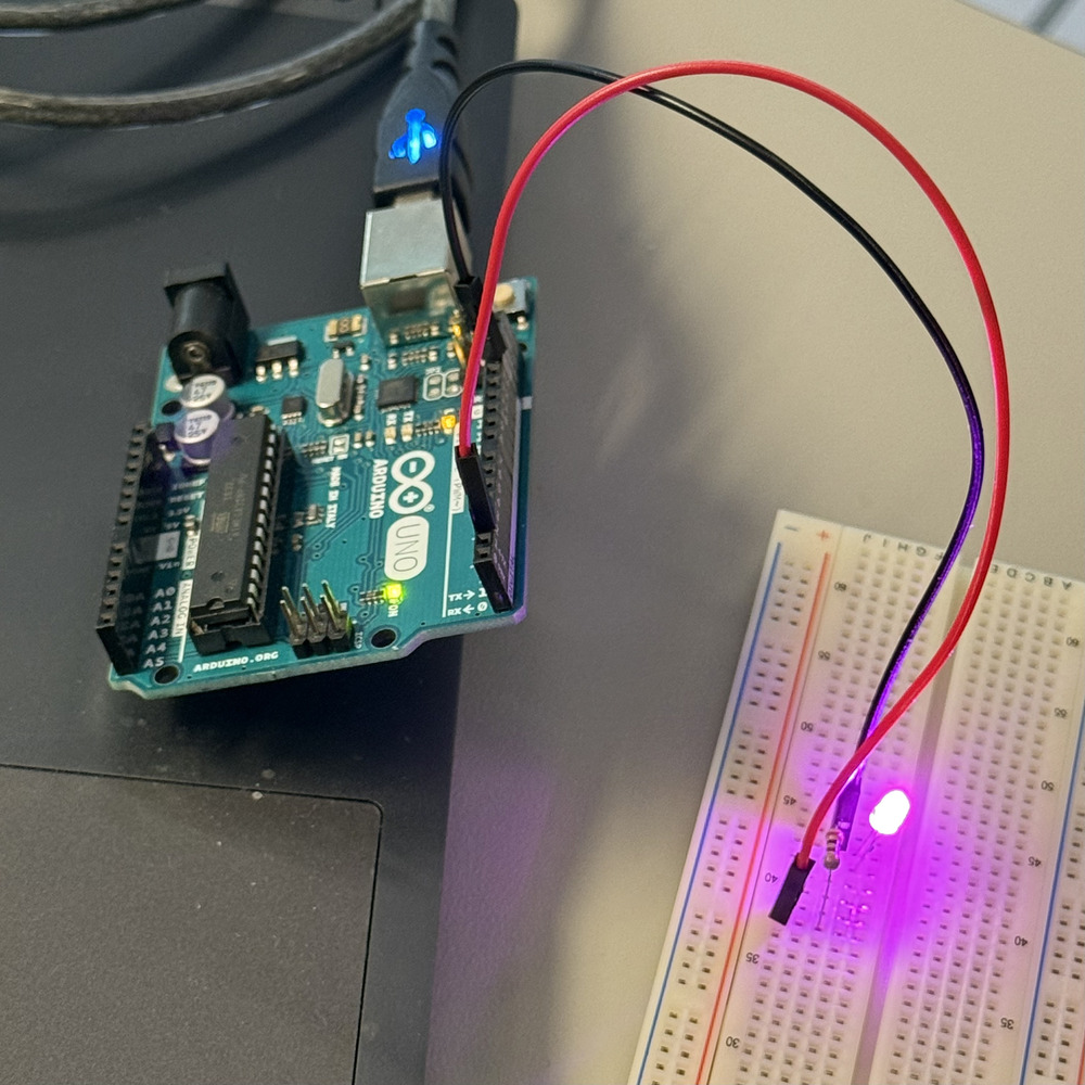 <b>Single LED circuit with jumper wires</b><br>I used jumper wires to connect a purple LED from the Arduino to the breadboard. The LED lights up clearly, showing that the current is flowing through the right path. I also added a resistor to protect the LED from too much power.